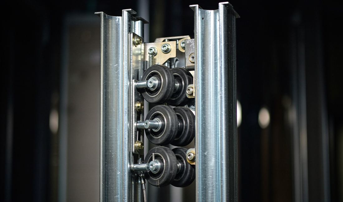 Close-up of polished steel elevator guide rails and roller assembly