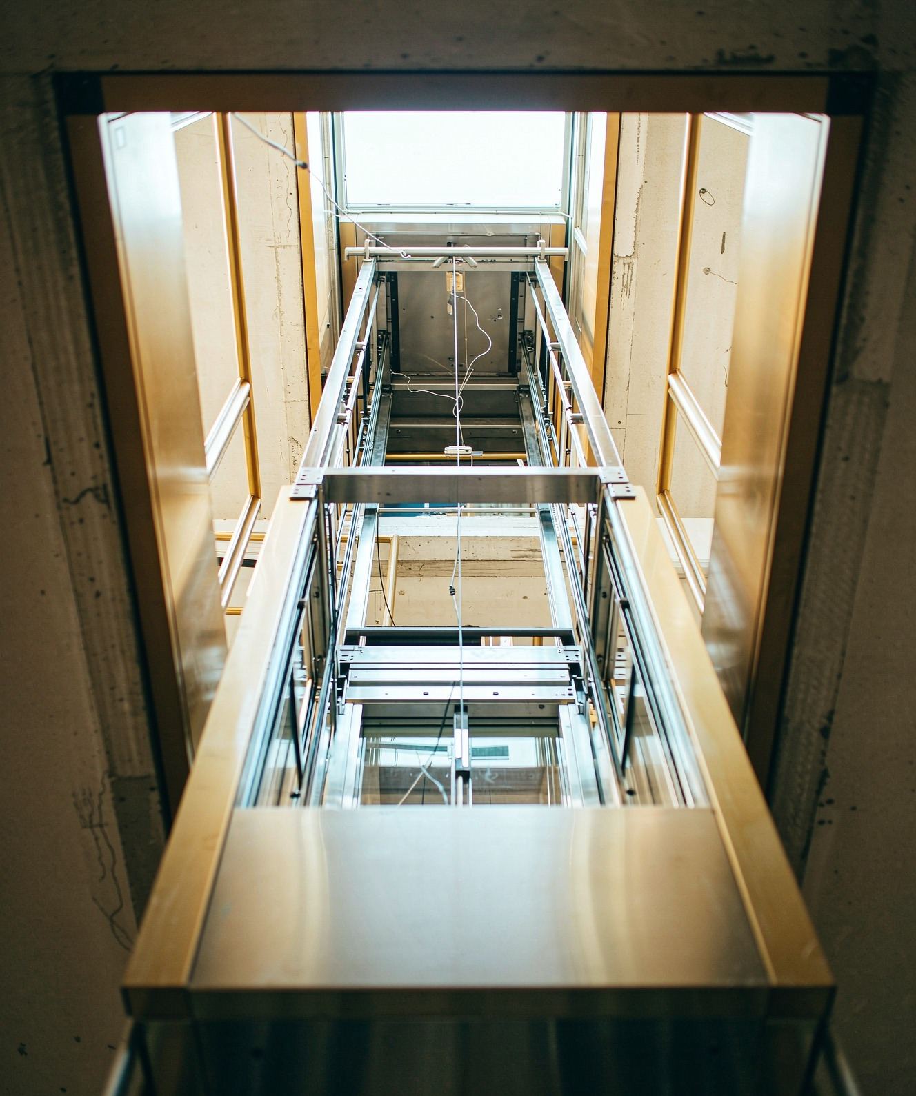 Looking up through an open stairwell shaft at a partially installed villa elevator frame