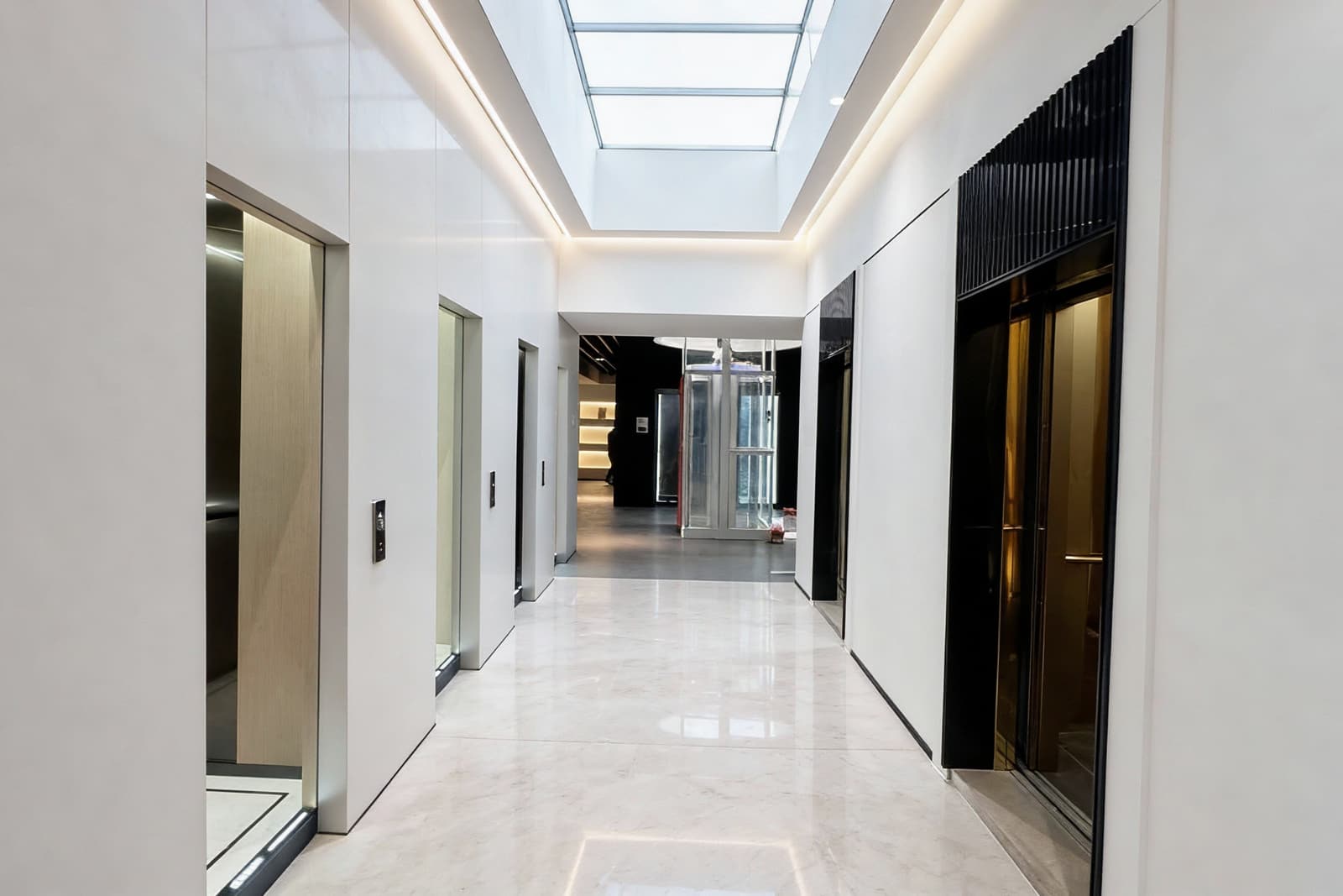 Bright SINNVO showroom gallery of landing doors under a long skylight, a glass elevator at the far end